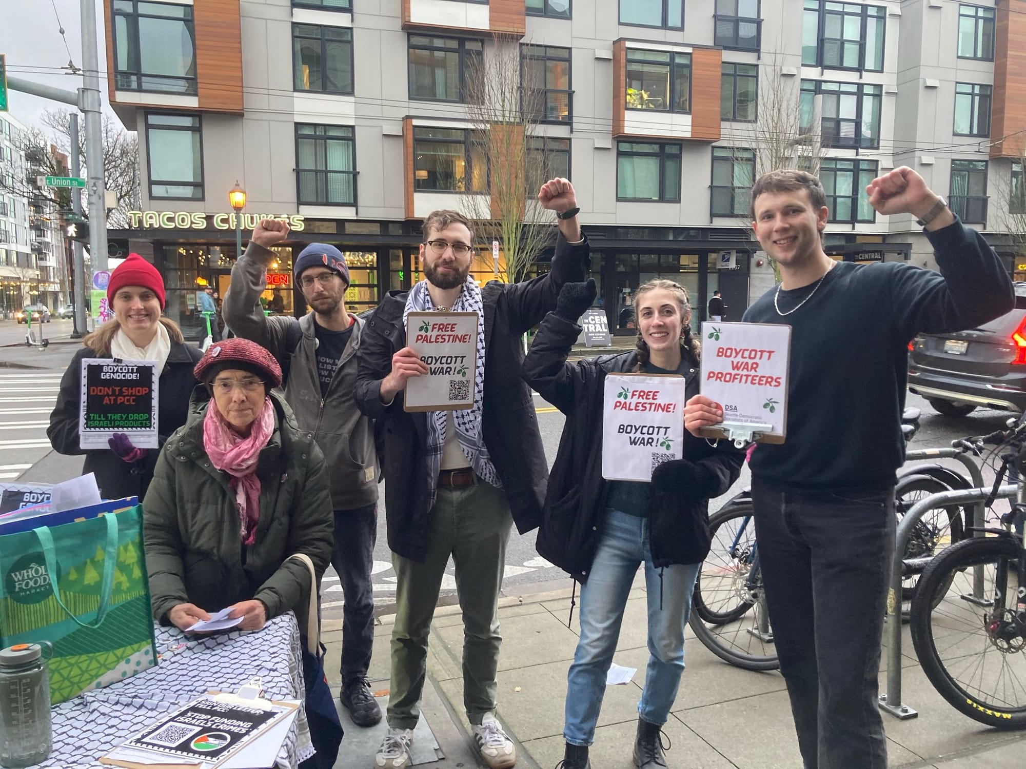 Six Activists pose for the camera with fists raised and signs in support of Palestine